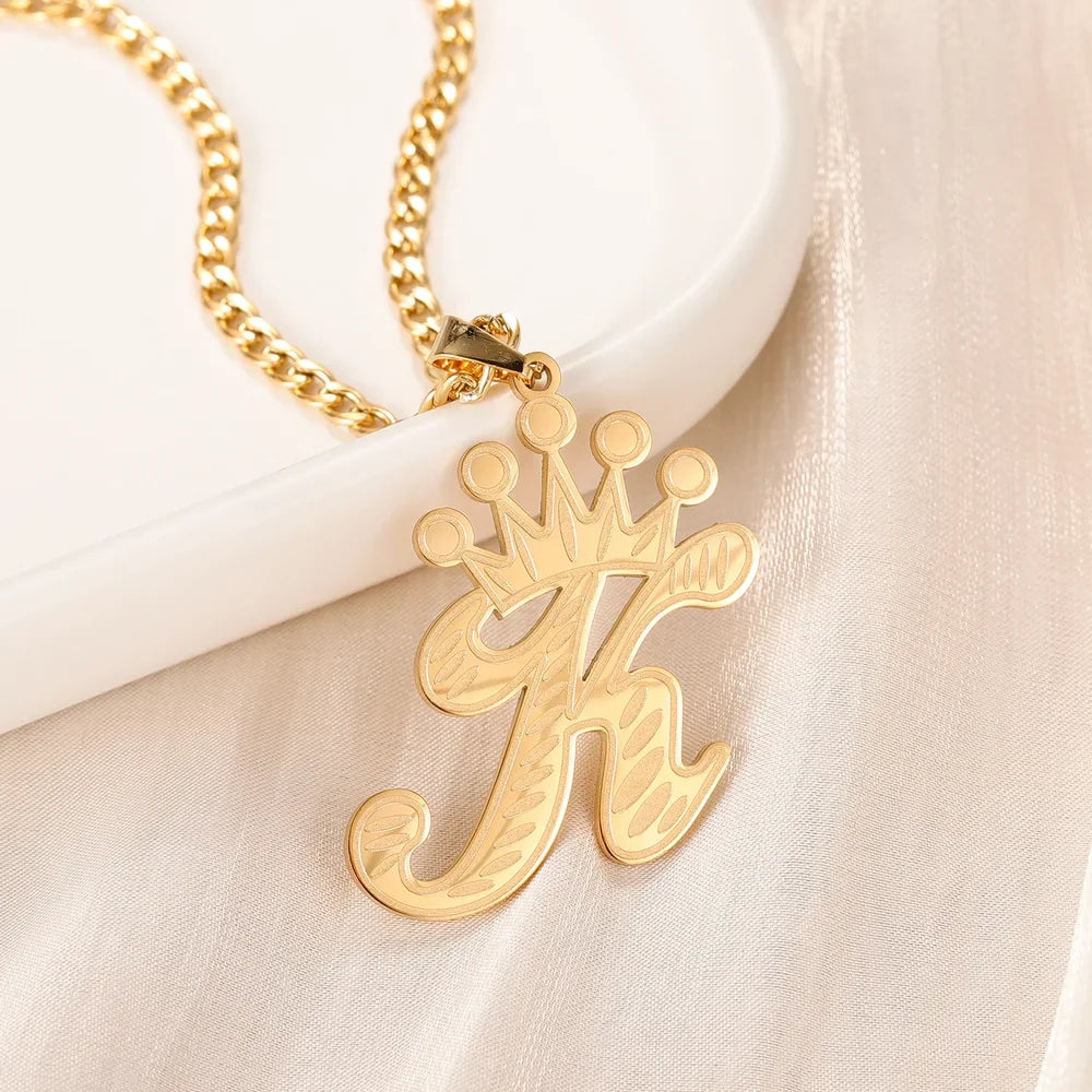 Gold Cursive Initial Crown Necklace for women displayed on a white surface