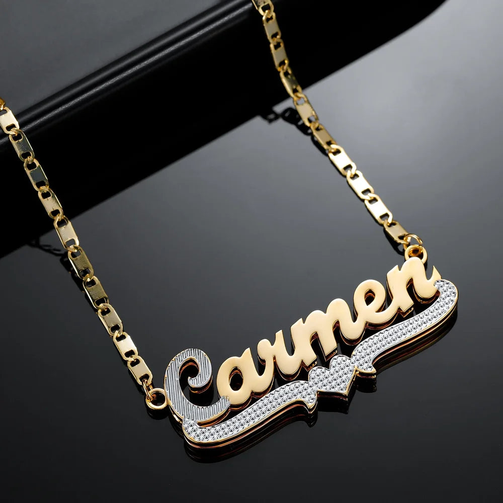  Double Plated Cursive Name Necklace in Gold with heart design element and Figaro chain, laid horizontally.