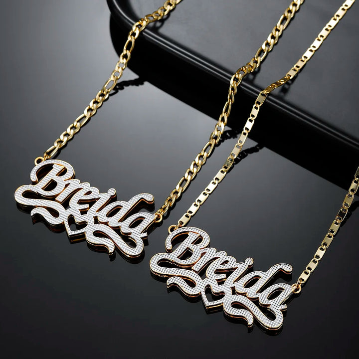 Two Double Plated Script Name Necklace in gold and with Figaro chains displayed together.