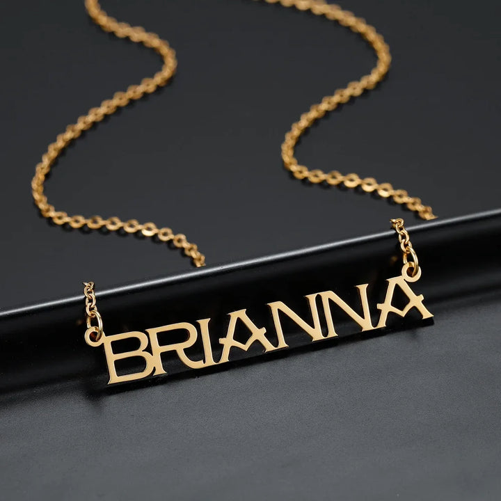 Gold capital letter name necklace on black surface