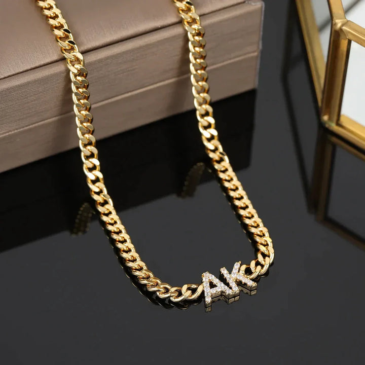 Close-up of iced initials necklace with cuban chain in gold