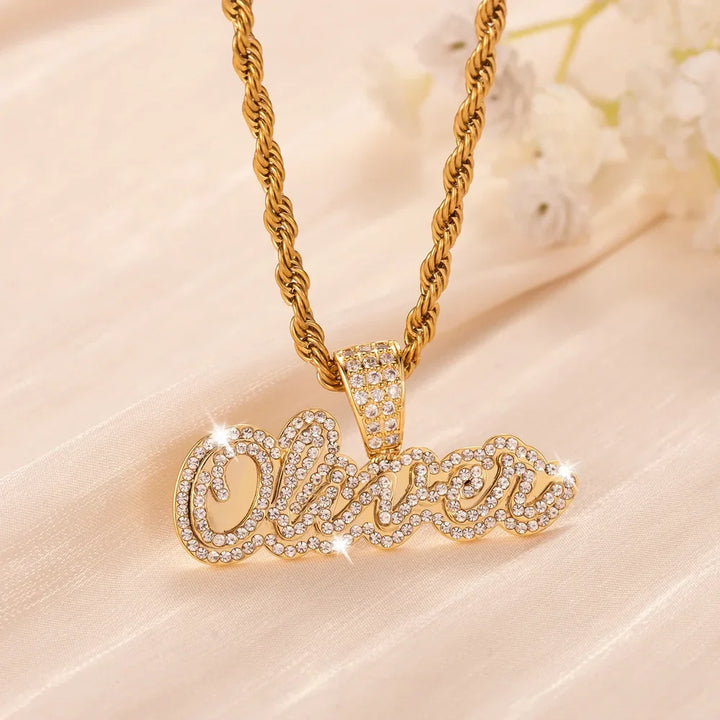 Iced Out Cursive Name Necklace in gold displayed on a soft fabric