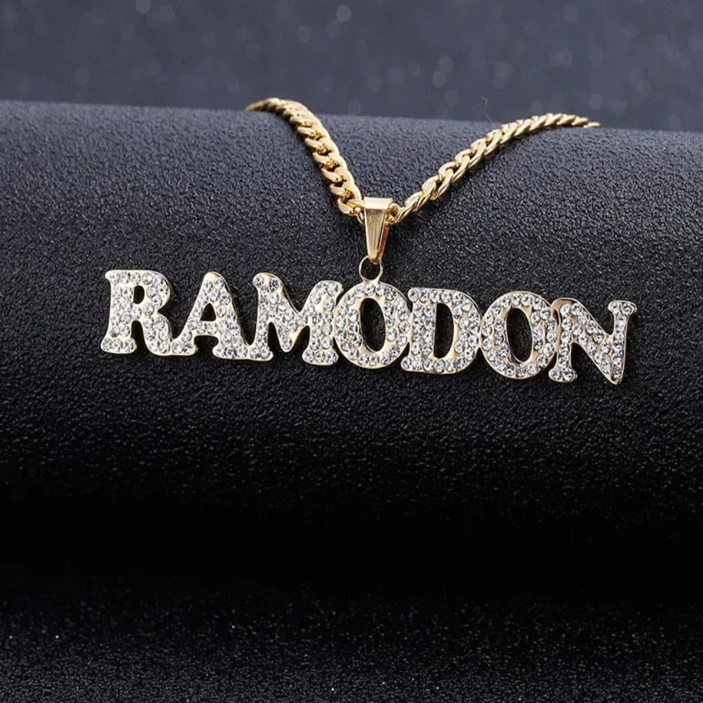 Iced Out Title Name Necklace with gold Cuban chain displayed on black background