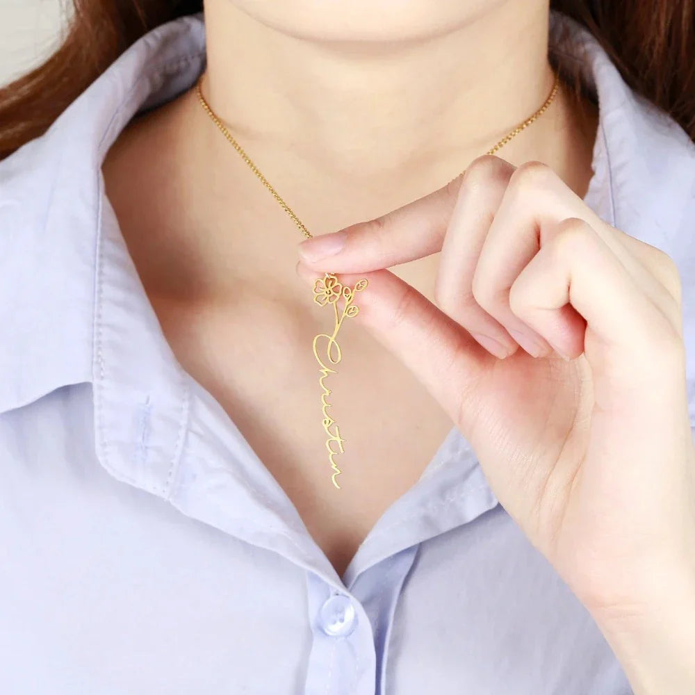 Model wearing a gold Personalized Birth Flower Name Necklace with the name 'Christina', holding the 18-inch (45cm) chain while displaying the delicate floral motif.