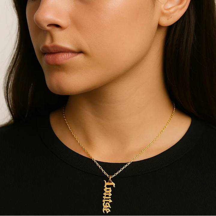 Woman wearing gold vertical Old English name necklace spelling "Louise".