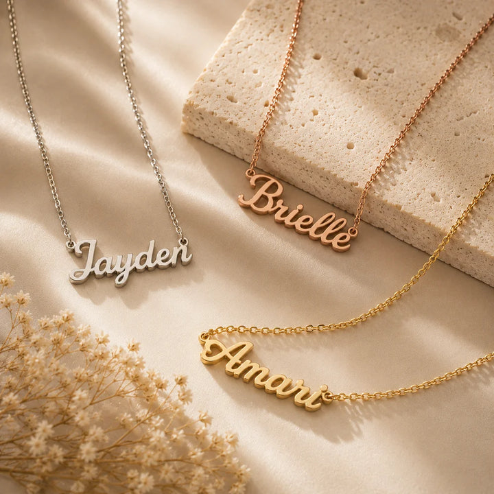 Three handmade cursive nameplate necklaces in gold, silver, and rose gold finishes displayed together