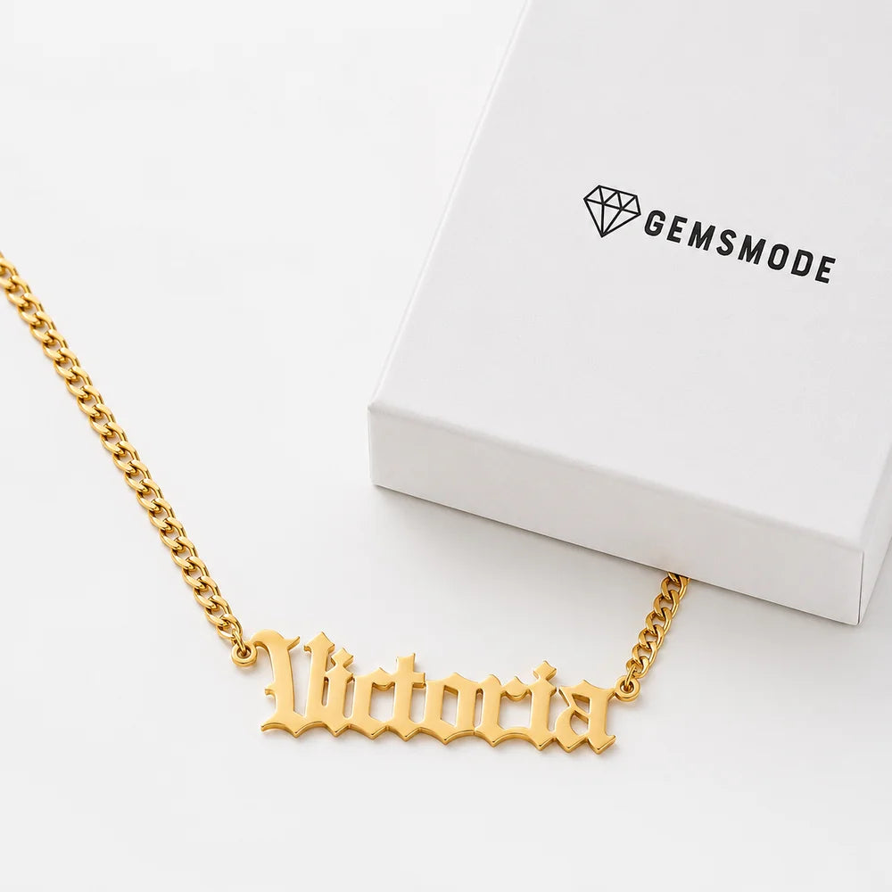 Personalized old english name necklace in gold with custom name "Victoria" displayed beside a gift box