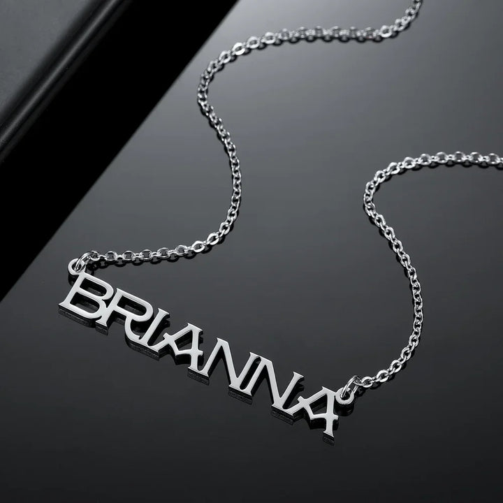 Silver capital letter name necklace on black surface